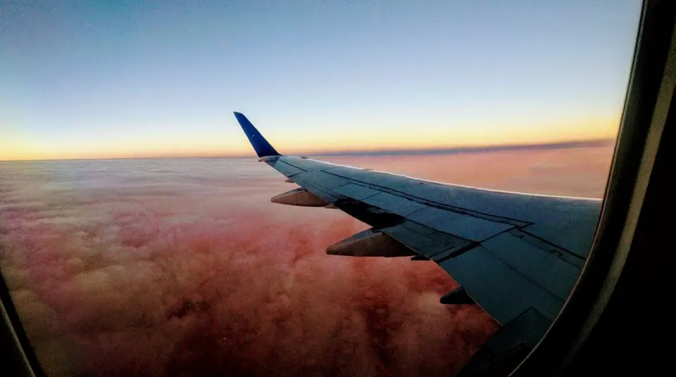 Ala di aereo sopra le nuvole al tramonto. Foto illustrativa senza legame documentato con una fabbrica marocchina o il salone.